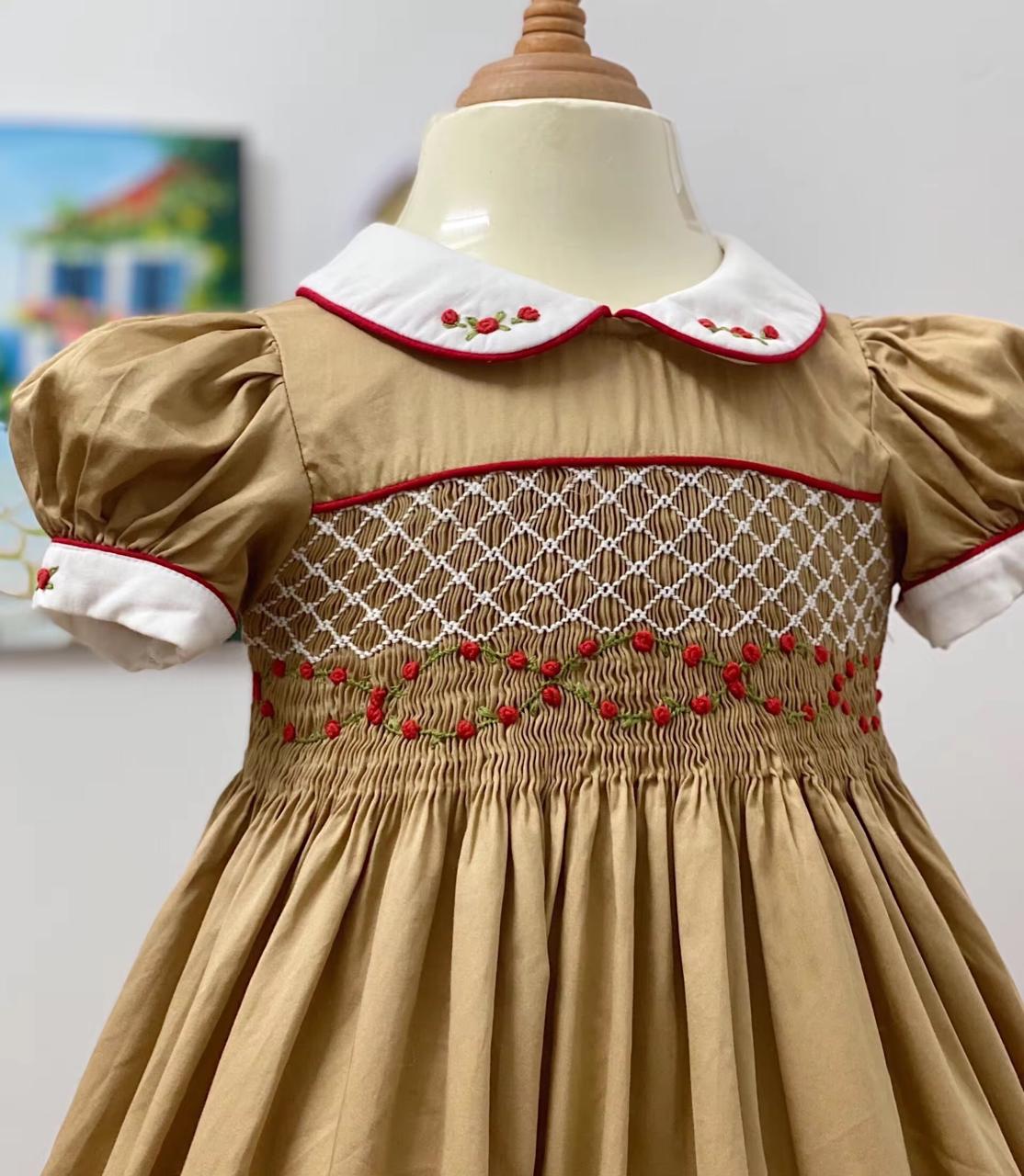 Three-quarter view of golden caramel smocked dress showing collar detail and full gathered skirt
