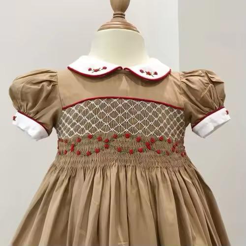 Close-up of smocked band showing trailing hand-embroidered red roses across the bodice panel