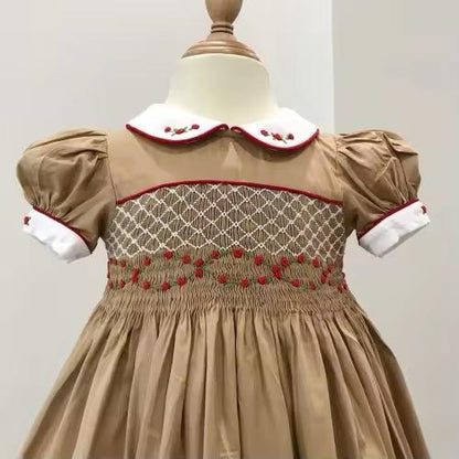 Close-up of smocked band showing trailing hand-embroidered red roses across the bodice panel