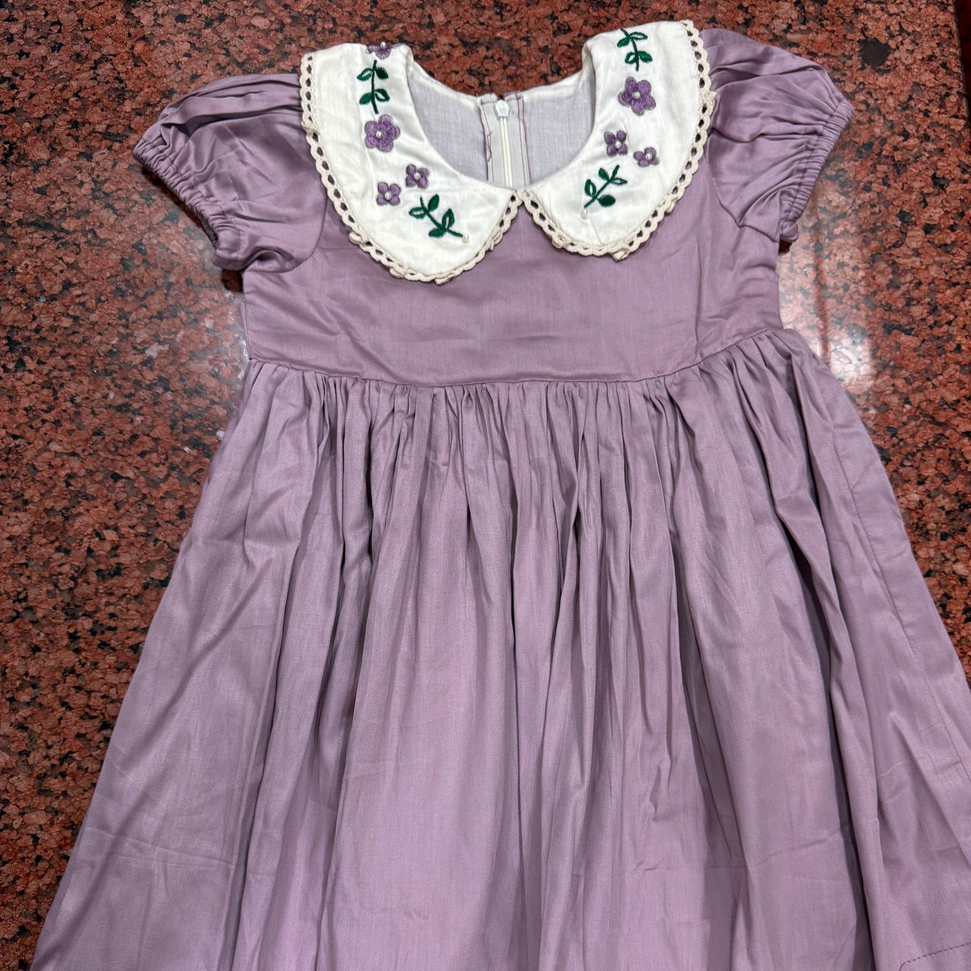 Full view of lavender hand embroidered girls dress laid flat
