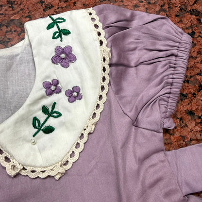 Close-up of white Peter Pan collar with hand-embroidered violet flowers and pearl centres