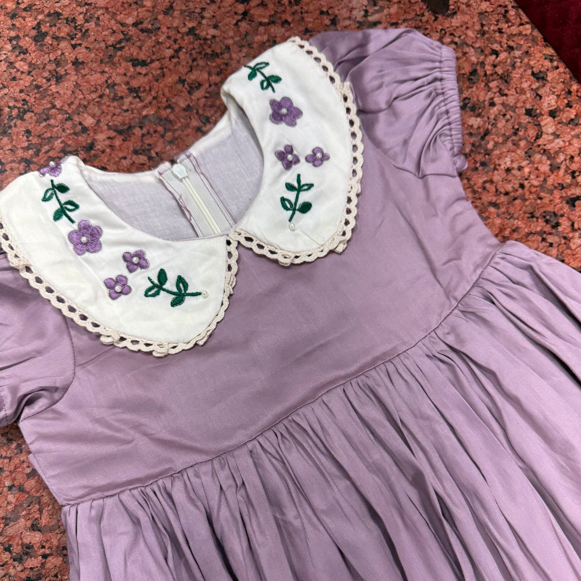 Detail of hand-embroidered violet collar with crochet lace edge and puffed sleeve