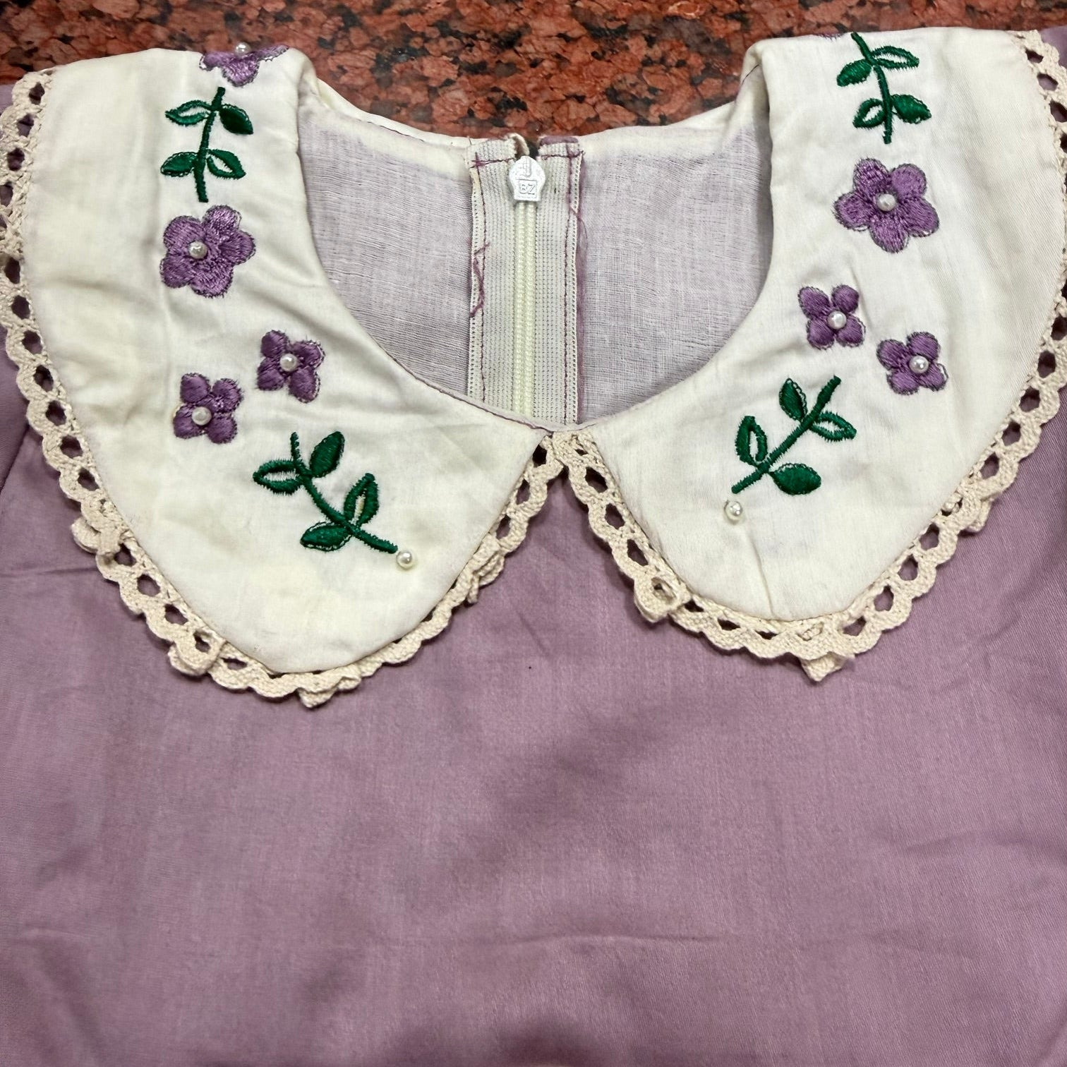 Angled view of lavender dress showing collar detail and pin-tuck hem