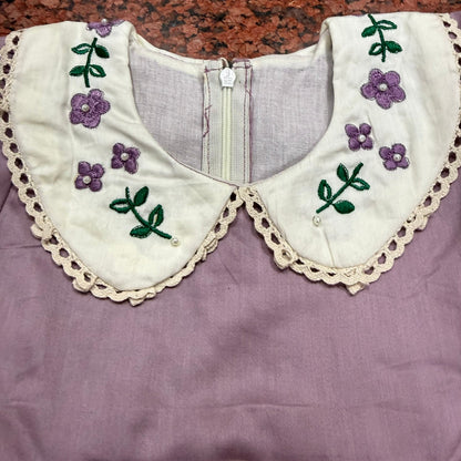Angled view of lavender dress showing collar detail and pin-tuck hem